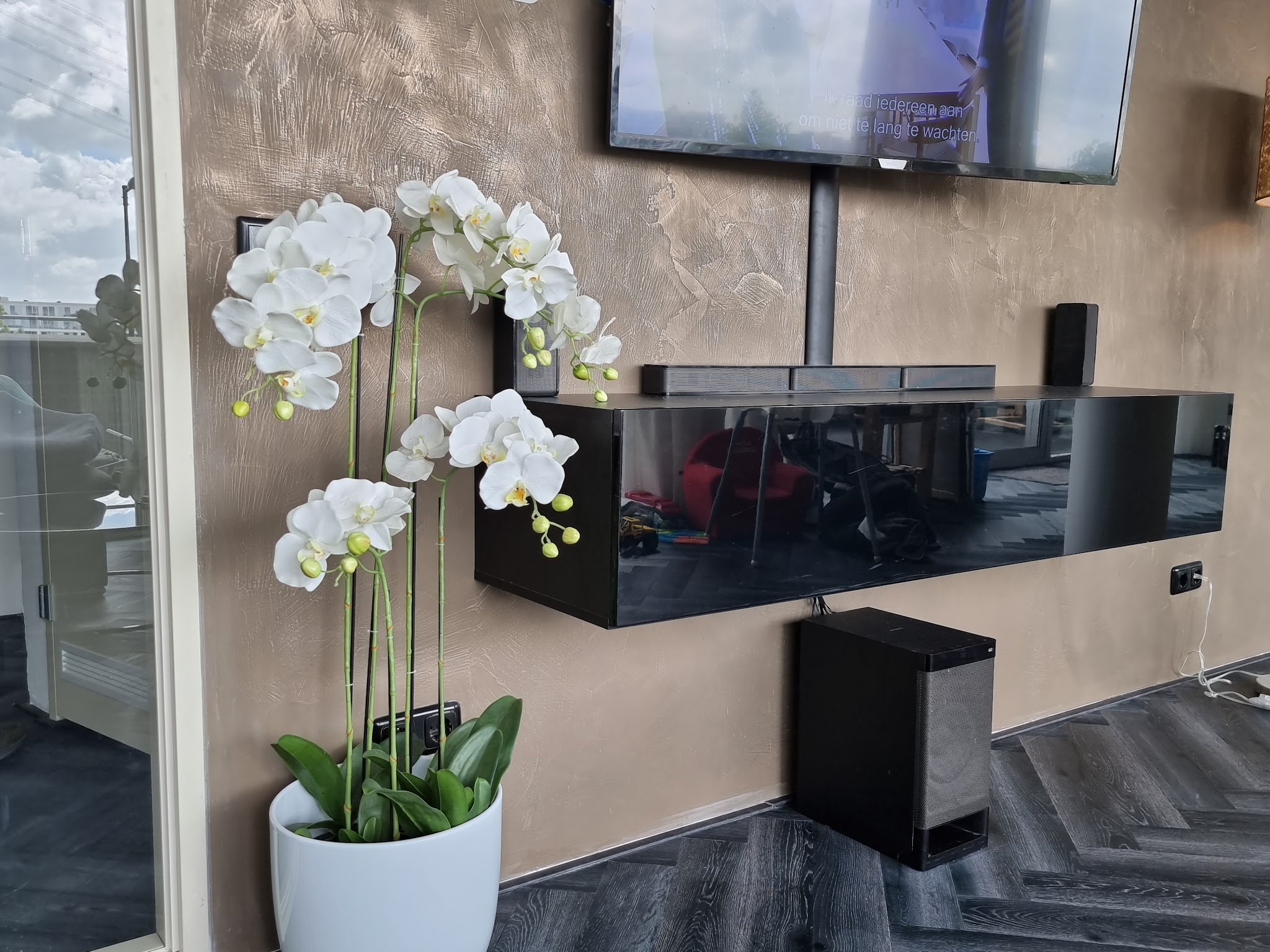 Tv-wand in bronskleurig metallic stucwerk met zwevend zwart kastje