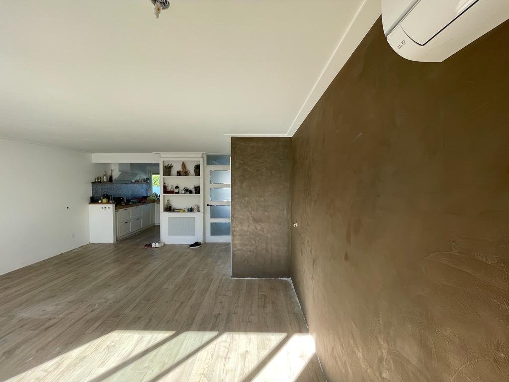Warme bronskleurige stucwand en kolom in een open woonkamer