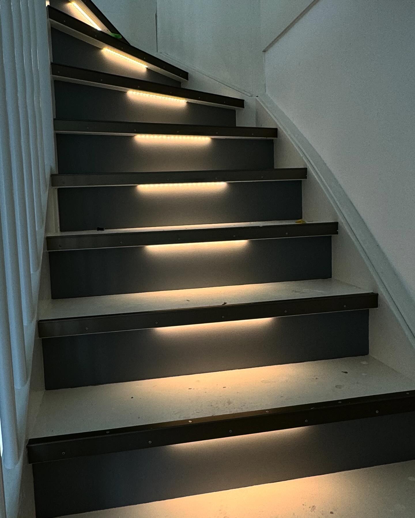 Trap met grijze stootborden en ledverlichting, wanden strak gestuct