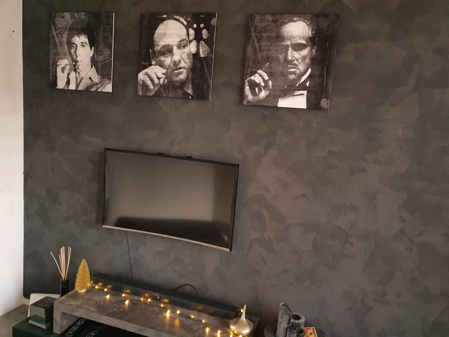 Donkergrijze betonlook wand met tv en drie canvassen